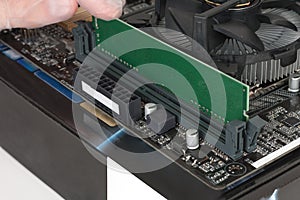 Close up of man hand with glove installing Ram DDR4 memory module in slot on motherboard