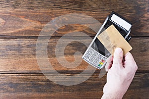 Close up of man hand holding bank card near payment terminal, Paypass technology concept