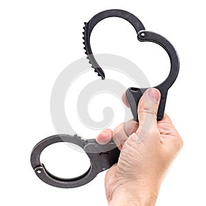 Close-up of man hand holding disclosed handcuffs, isolated on white background