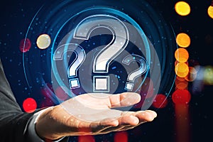 Close up of man hand holding glowing round question mark hologram on blurry bokeh background. FAQ and customer service concept.