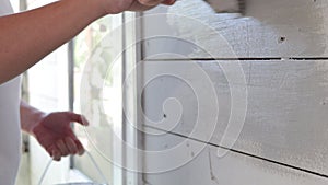 Close up of man hand painting exterior wooden wall of a house, painter working