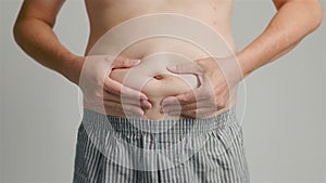 close up of man hand pinching excessive belly fat