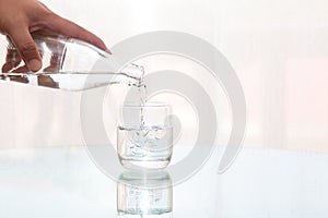 Close up man hand pouring fresh filtered purified water from a bottle into a glass