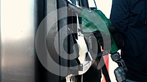 Close up of man hand putting out a green fuel nozzle. Gasoline fuel, gas station concept Truck station