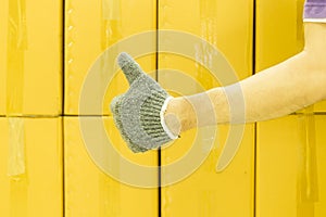 Close-up of man hand with thumb up in front of cardboard boxes, likes or approves concept