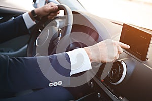 Close-up of a man hand touching black screen smartphone on a dashboard.