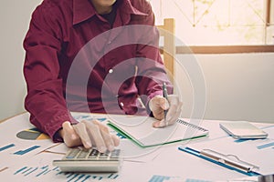 Close up man hand using calculator Calculating bonusOr other compensation to employees to increase productivity.