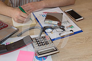 Close up Man hand using calculator and writing make note with calculate about cost at home office