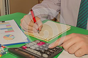 Close up Man hand using calculator and writing make note with calculate about cost at home office. Business concept. The Man are