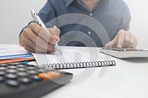 Close up man hand using calculator and writing make note with calculate about cost at sale office