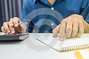 Close up man hand using calculator and writing make note with calculate about cost at sale office