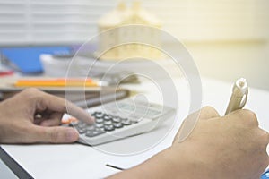 Close up man hand using calculator and writing make note with calculate about cost at sale office