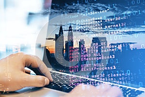 Close up of man hand using laptop keyboard with abstract html code on creative city background. Coding and programming concept.