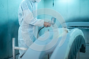 Close-up man hand is using painting gun in repair mechanic painting shop