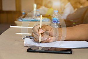 close up man hand using pencil for writing on sheet between meeting in room