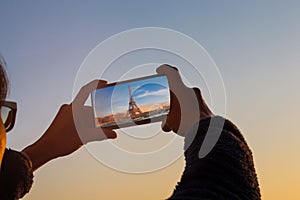 Close up of Man hand using smartphone taking a picture the landmark at Eiffel tower in Paris ,France and sunset sky scene