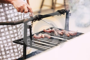 Close up of man hands cooking fresh meat on a old style wood and fire barbecue bbq grill - home celebration for people love to eat