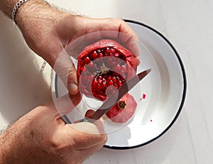 Top view of man hands cutting pomegranate with a knife