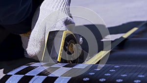 Close up of man hands cutting and measuring roofing material. Clip. Worker in white gloves using construction roulette