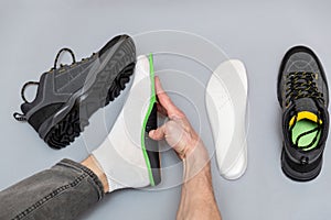 Close up of man hands fitting orthopedic insoles on a gray background