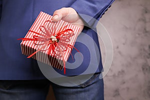 close up of man hands holding gift box behind his back