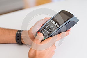 Close up of man hands holding point of sale terminal, dataphone for shopping paying using credit card