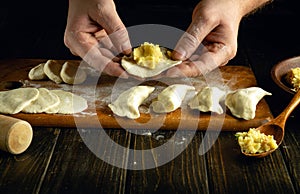 Close-up of a man hands making dumplings on the kitchen table for dinner. The concept of preparing dumplings in the kitchen of a