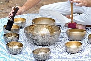 Close-up of man hands playing on a singing tibetian bowl with sticks. Sound healing music instruments for meditation