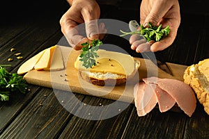 Close-up of a man hands preparing a sandwich on a kitchen board. The concept of preparing a quick meal at home. Advertising space