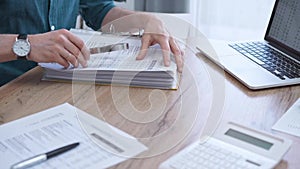 Close-up of man hands reviewing financial documents with magnifying glass. Business work process in bookkeeping office