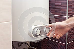 Close-up of man hands setting the temperature of water in Electric Boiler.