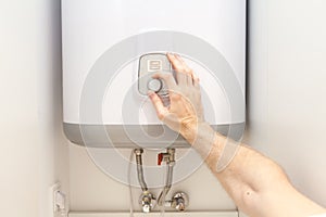 Close-up of man hands setting the temperature of water in Electric Boiler.