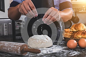 Close up of Man hands sprinkling flour over fresh dough with ing