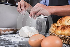 Close up of Man hands sprinkling flour over fresh dough with ing