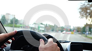 Close up of man hands on steering wheel. Slow motion. Male driving a car on road spinning wheel. Highway on background