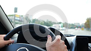 Close up of man hands on steering wheel. Slow motion. Male driving a car on road spinning wheel. Highway on background