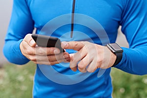 Close up of man hands syncing smart watch and phone outdoor