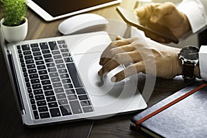 Close-up of man hands using keyboard of laptop computer on office desk.