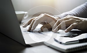 Close-up of man hands using and typing keyboard of laptop computer on office desk.