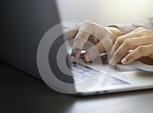 Close-up of man hands using and typing keyboard of laptop computer on office desk.