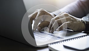 Close-up of man hands using and typing keyboard of laptop computer on office desk.