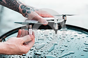 Close up of Man Holding Black Drone Quadcopter at Black Wet Metalllic Background. Remote Controlled Wireless Quadcopter