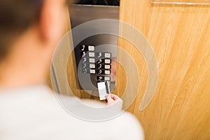 Close up of man holding cardkey on control panel elevator access concept