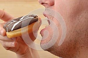 Close up of a man holding a delicious doughnut with chocolate an