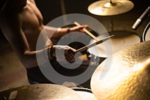 Close-up of man holding drumstick and playing drums and cymbals