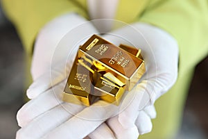 Close-up of man holding gold bars in his hands.