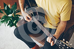 Close-up of a man holding a guitar and learning guitar chords for beginners. Feeling happy and inspired. Spending time wisely