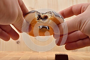 Close up of a man holding in his hands a bite doughnut with choc