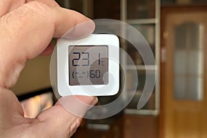 Close-up of a man holding a hygrometer. Temperature and humidity readings in a room at home