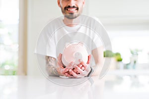 Close up of man holding piggy bank, saving money for investment smiling